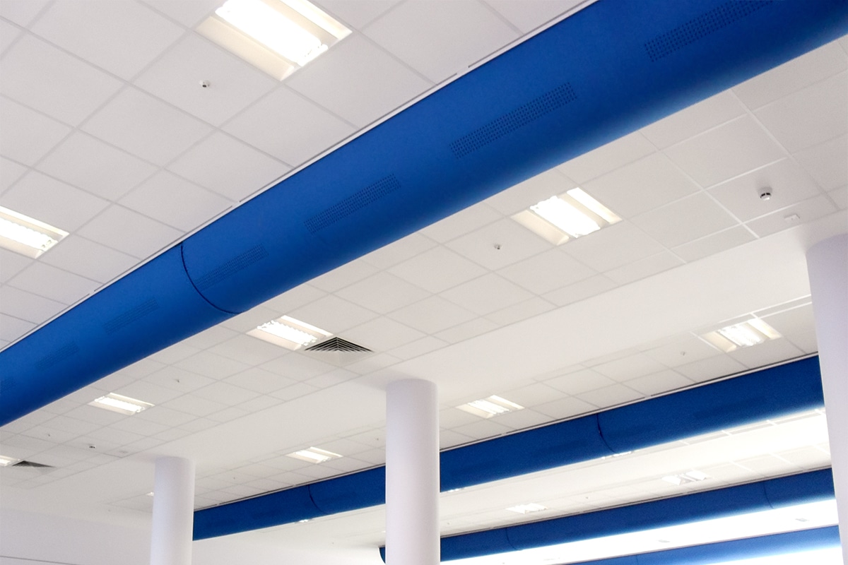 Blue fabric ducts with blocks of laser-cut perforations on a white ceiling